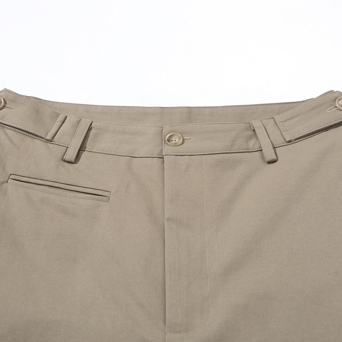 Close-up of taupe trousers showing the waistband, button, belt loops and front welt pocket.