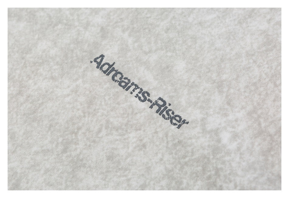 Close-up of dark printed lettering on the mottled light gray shirt fabric.