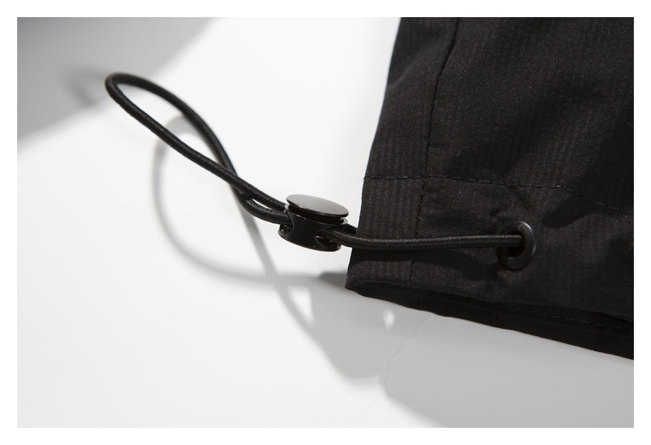 Close-up of a black garment hem with an elastic drawcord and toggle.