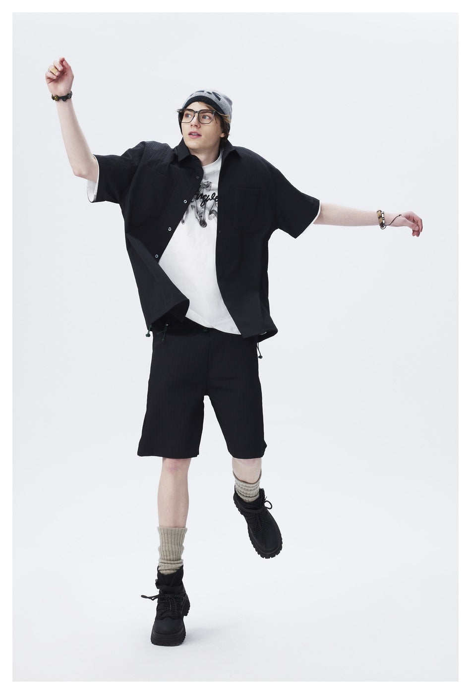 Full-length model wearing a black short-sleeve shirt and matching shorts over a white graphic T-shirt.