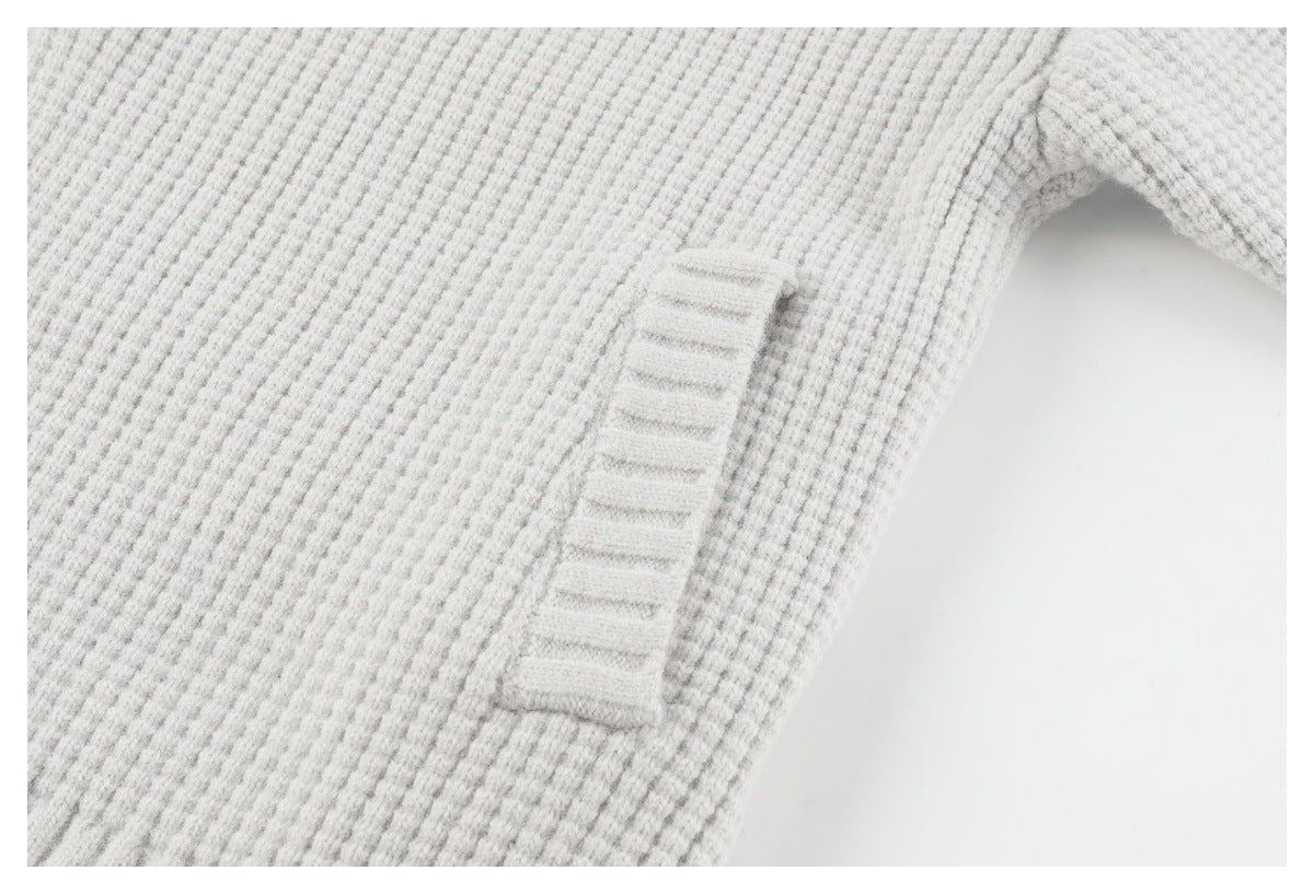 Close-up of a pocket opening on the light gray cardigan, showing its textured knit and ribbed trim.