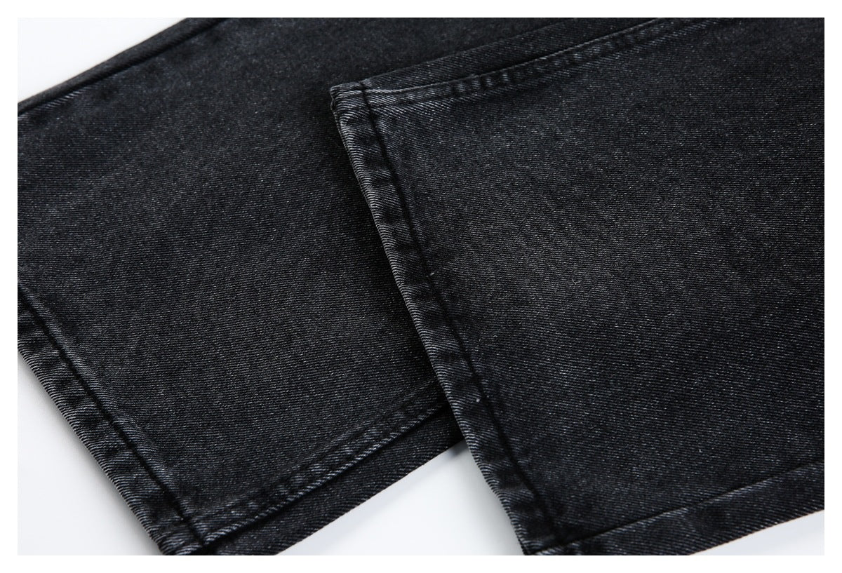 Close-up of black denim jeans showing the diagonal weave and stitched hems.