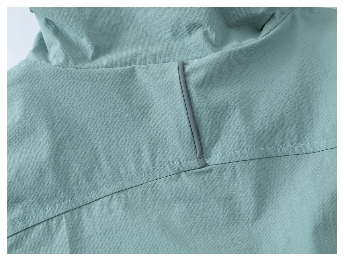 Close-up of pale teal jacket fabric with a curved stitched seam and narrow gray trim.