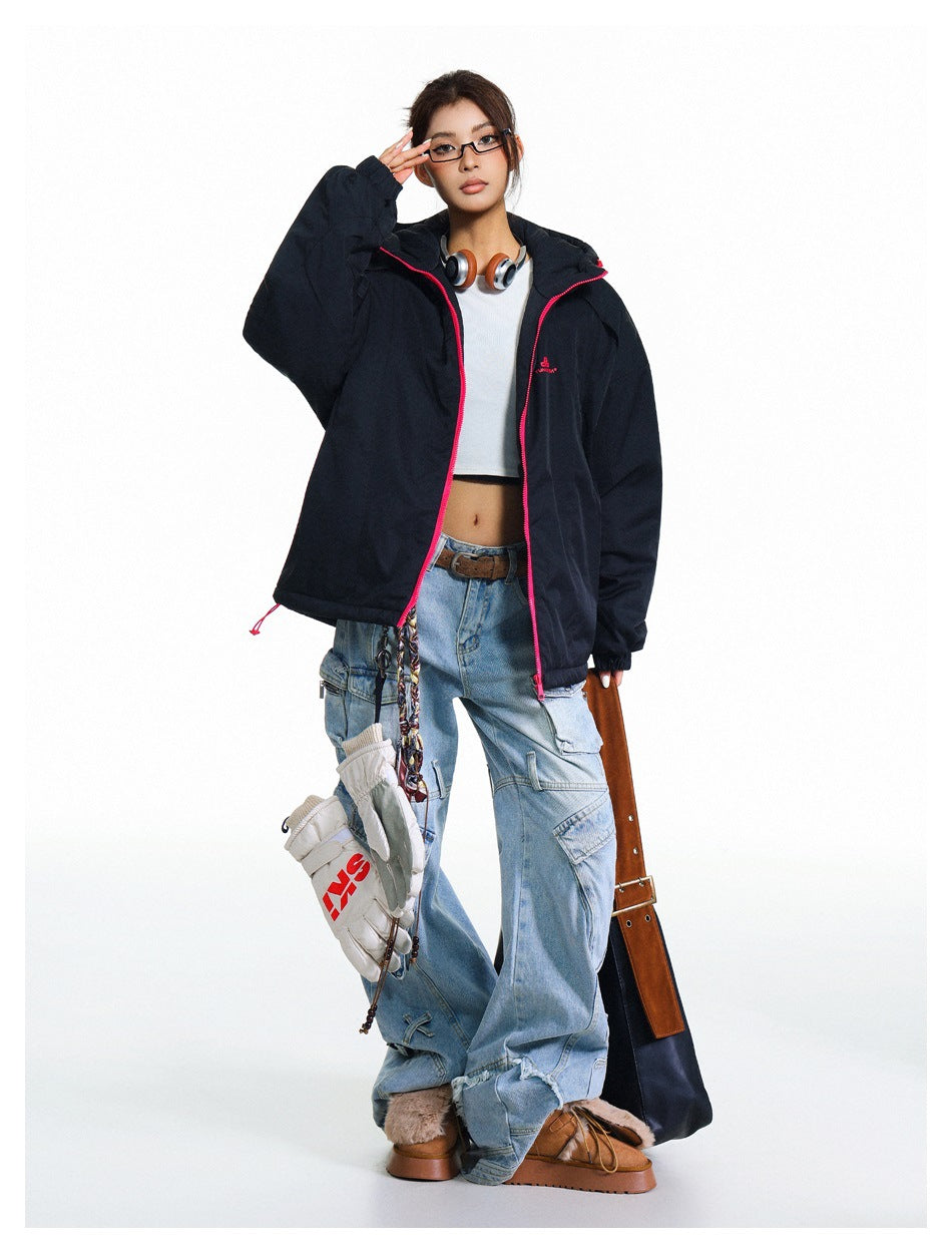 Model wearing an open black hooded jacket with bright pink trim over a white cropped top and light blue cargo jeans.