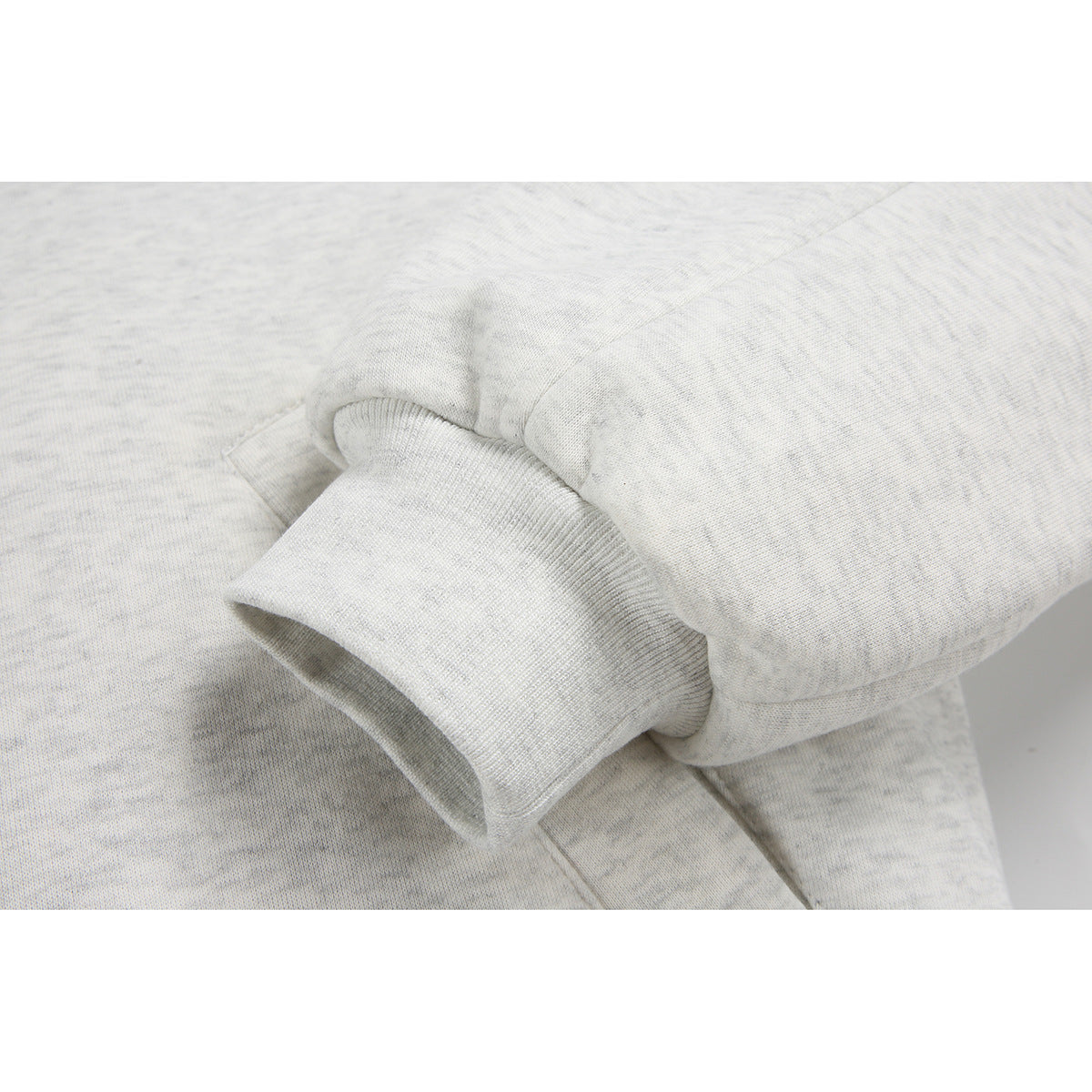 Close-up of the light gray jacket's ribbed sleeve cuff and seam.
