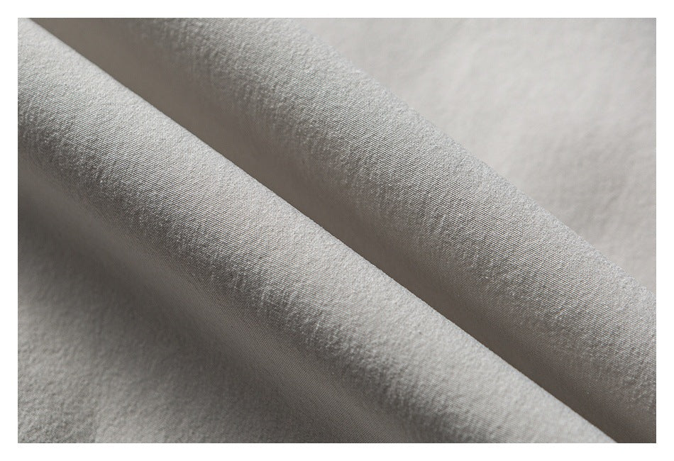Macro view of the fine texture and folds of light gray-white shirt fabric.