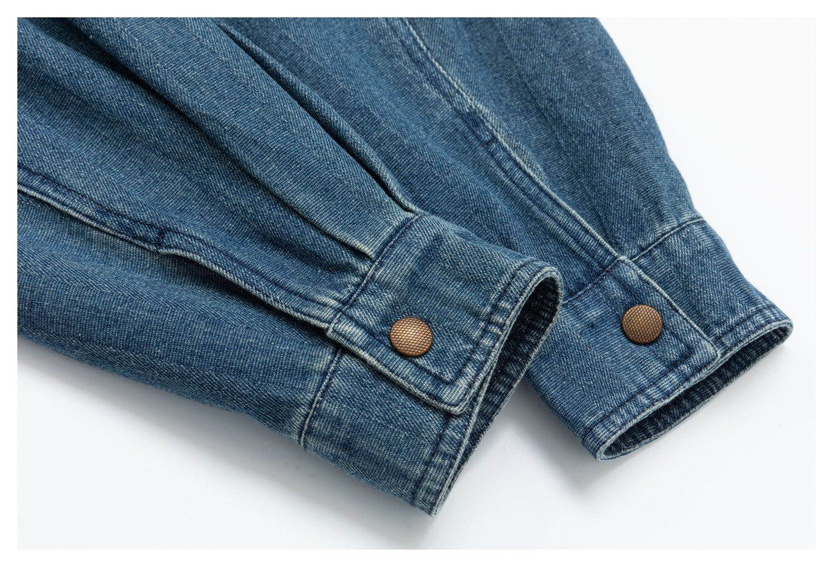 Close-up of blue denim sleeve cuffs with copper-colored snap buttons and stitched edges.
