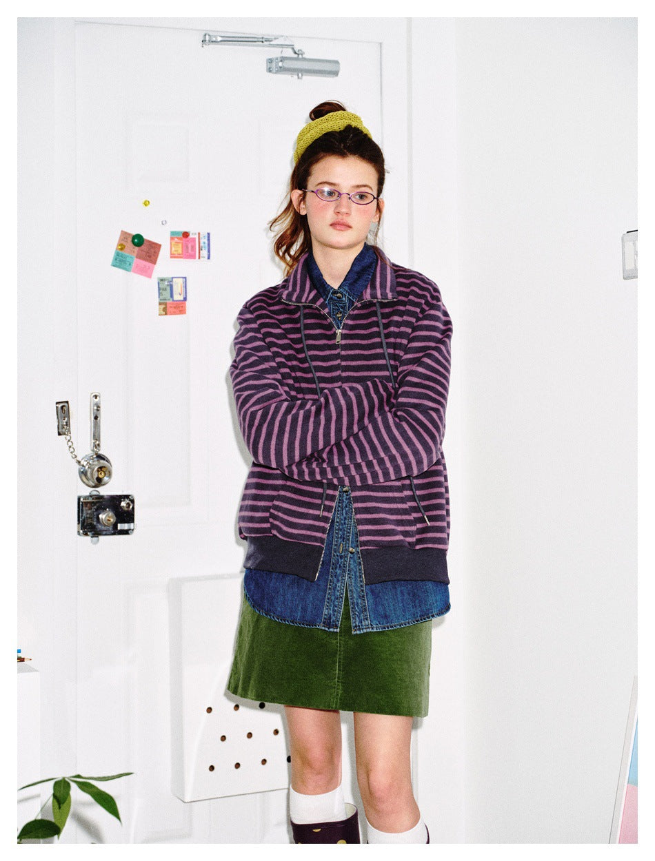 Front view of a model wearing a purple and black striped zip-front jacket with dark cuffs, hem and drawstrings.