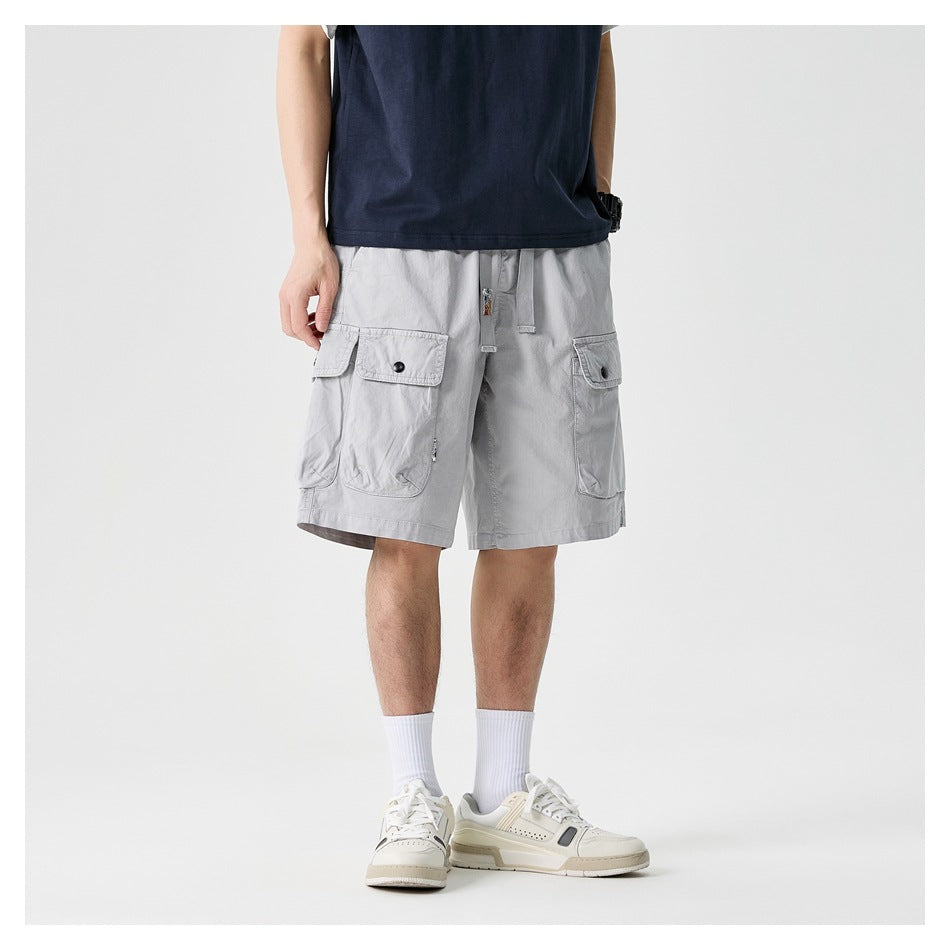 Front view of light gray cargo shorts with flap pockets and drawstring, worn with a navy shirt.
