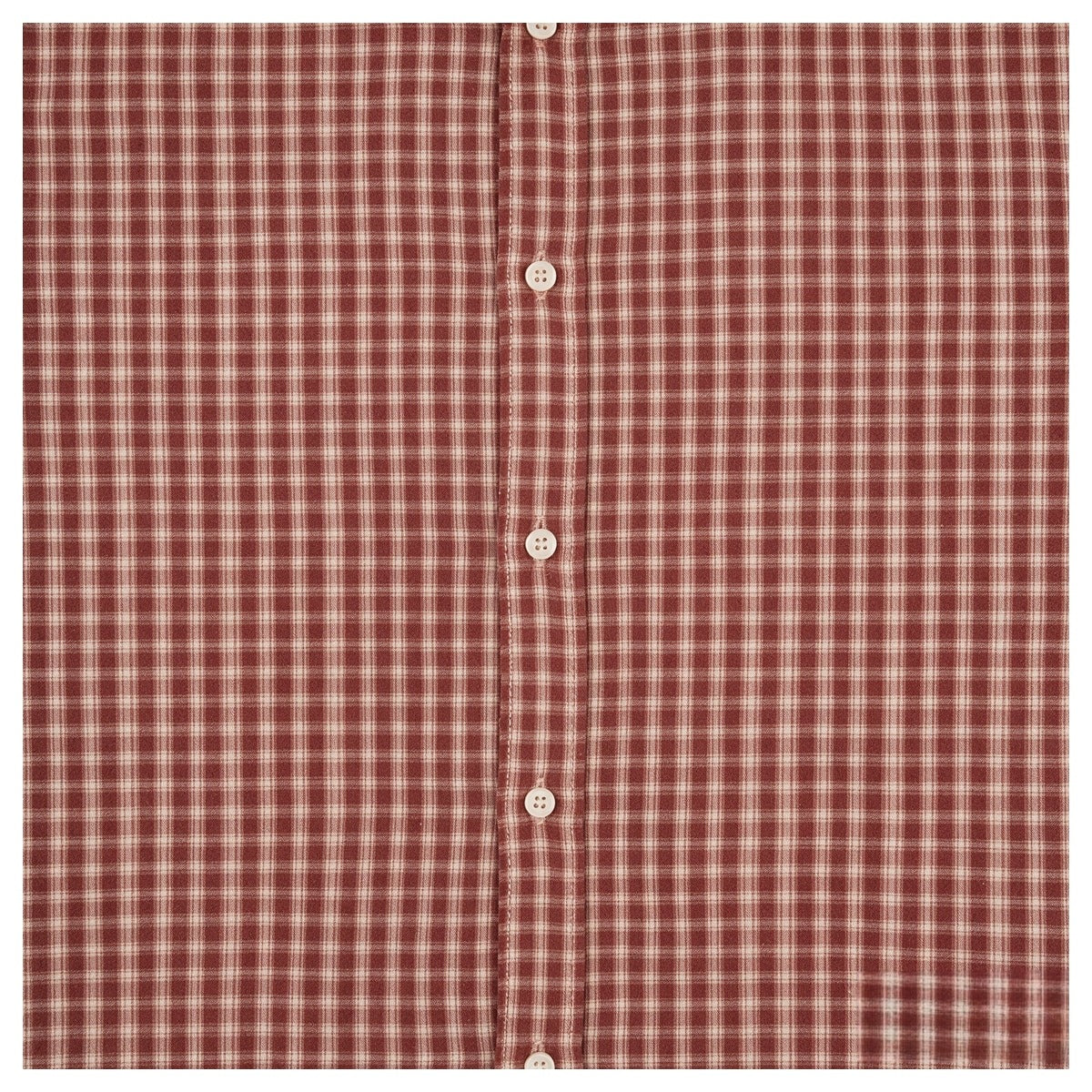 Close-up of a rust-red and cream plaid shirt front with a vertical placket and pale buttons.