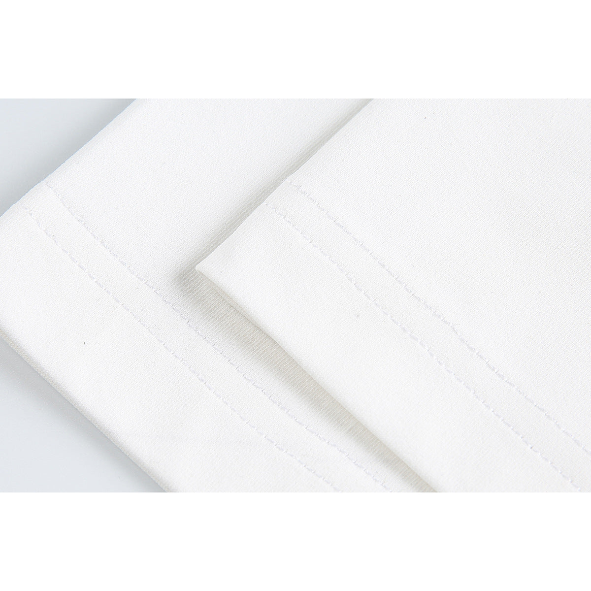 Close-up of stitching along the hem of a white T-shirt.