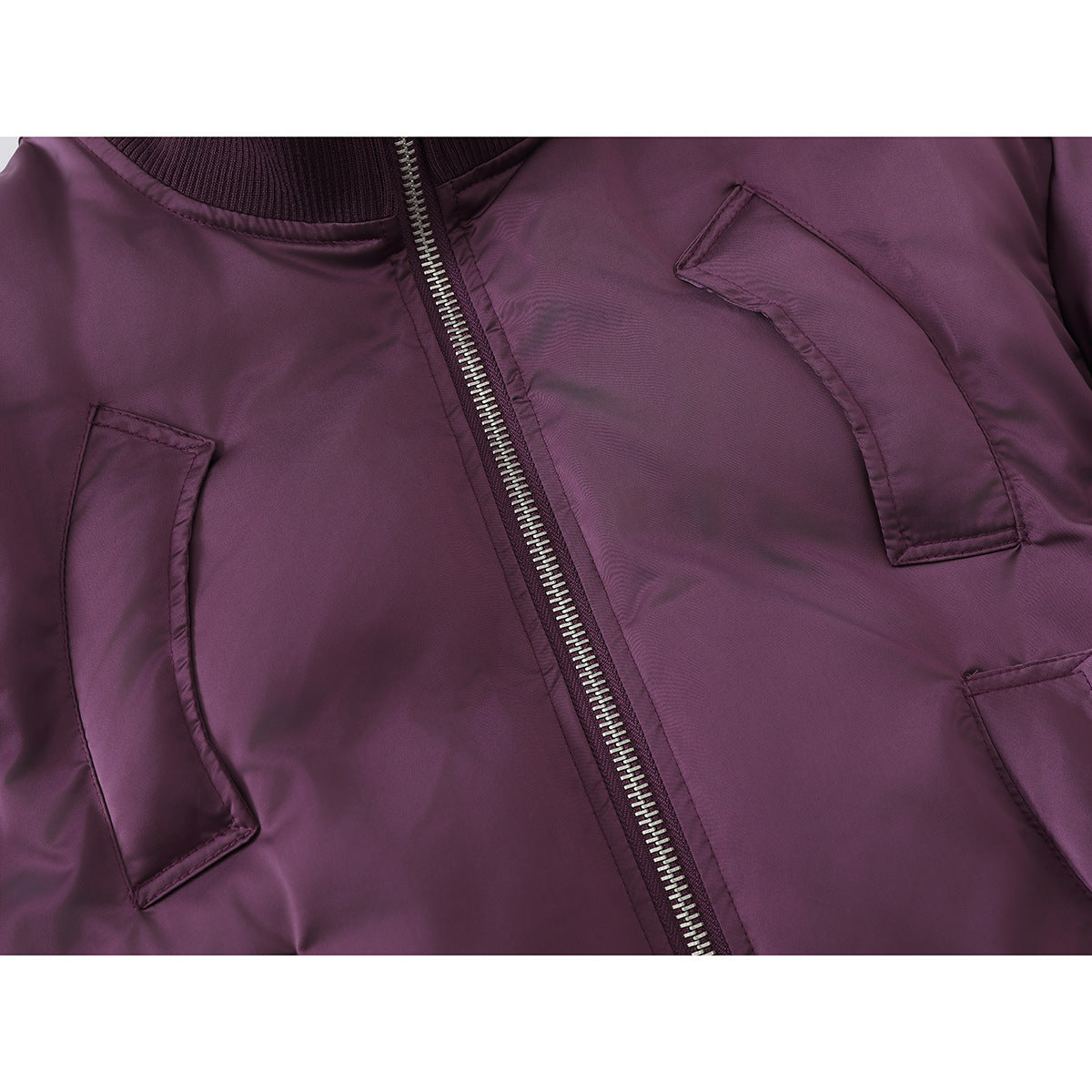Close-up of a plum jacket’s front zipper and curved stitched pocket details.