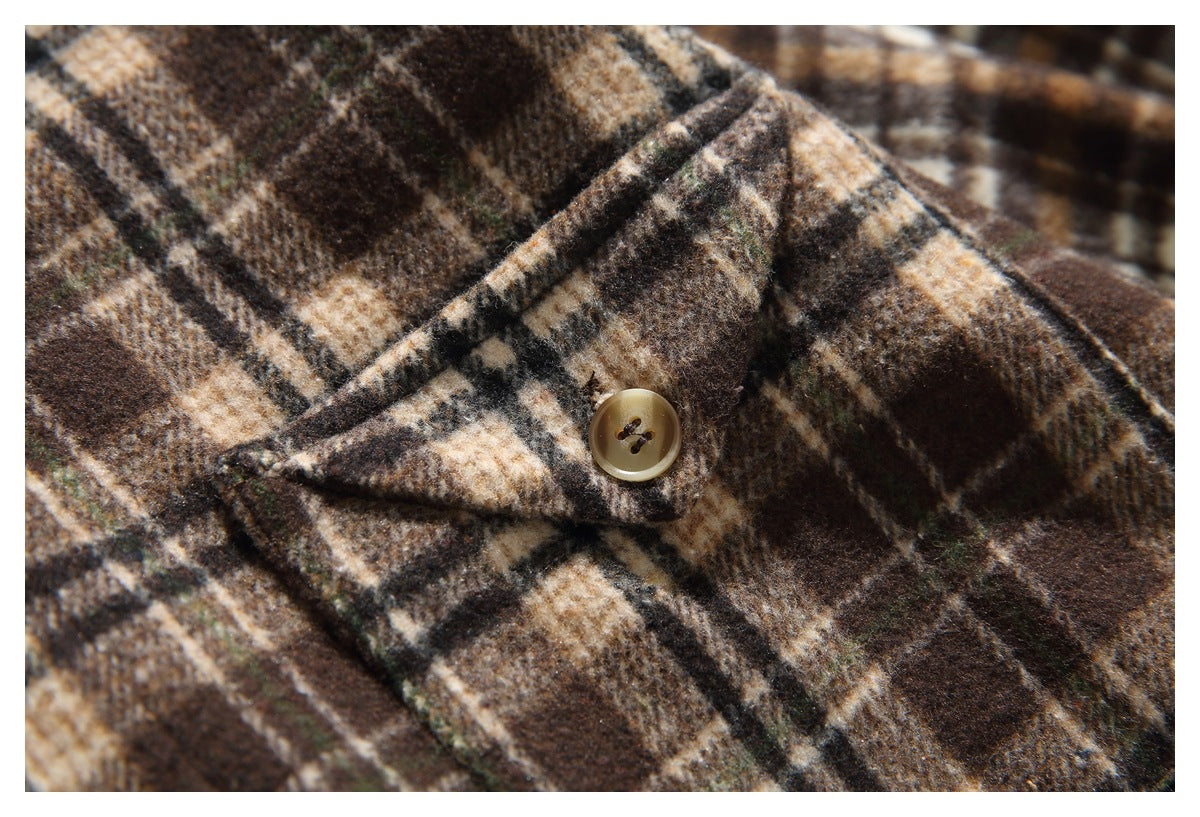 Close-up of a tan button on the brown, cream, and black plaid shirt front.