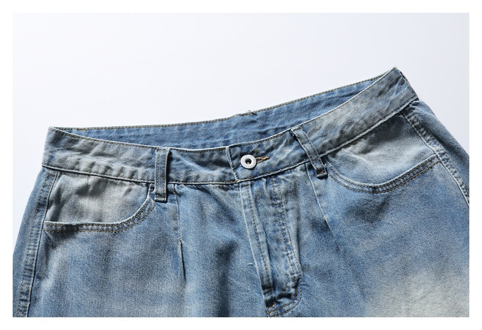 Close-up of the front waistband, button and pockets on faded blue denim shorts.