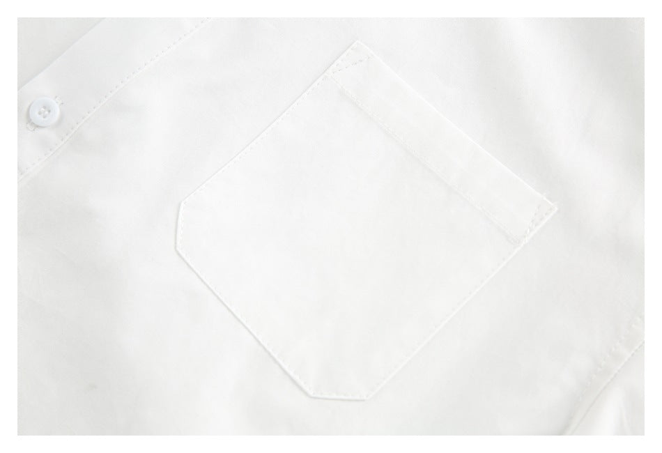 Close-up of a white shirt's chest pocket and a white button.