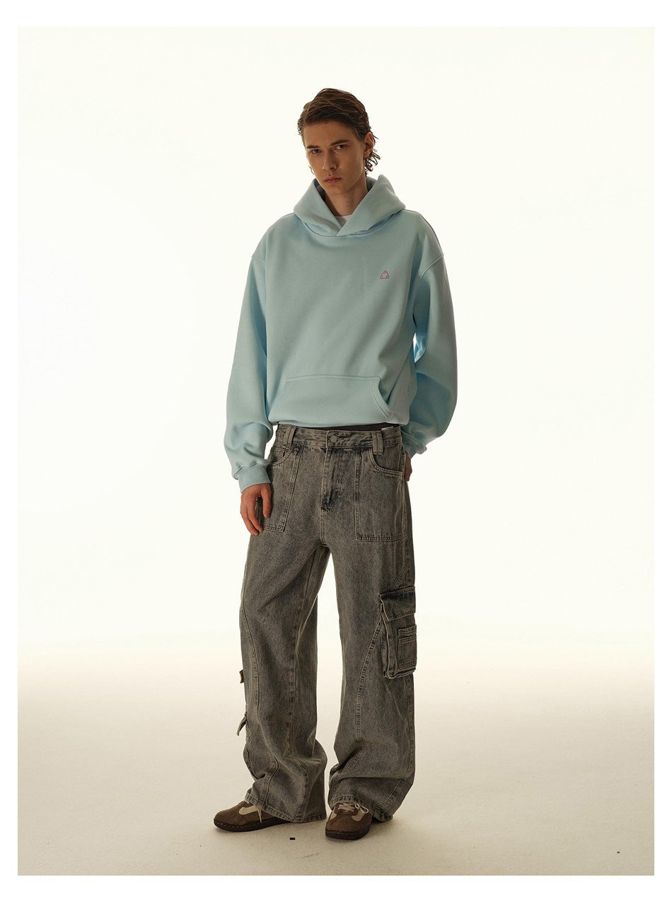 Model wearing a pale blue oversized hoodie and loose gray cargo jeans, shown nearly front-on.