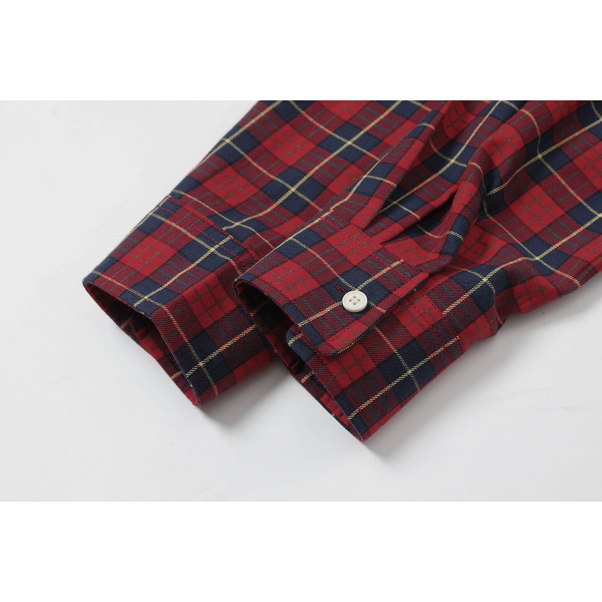 Close-up of the red and navy plaid shirt's buttoned sleeve cuffs.