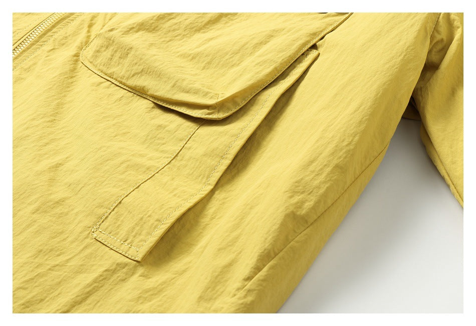 Close-up of a mustard-yellow jacket's large flap pocket and front stitching.