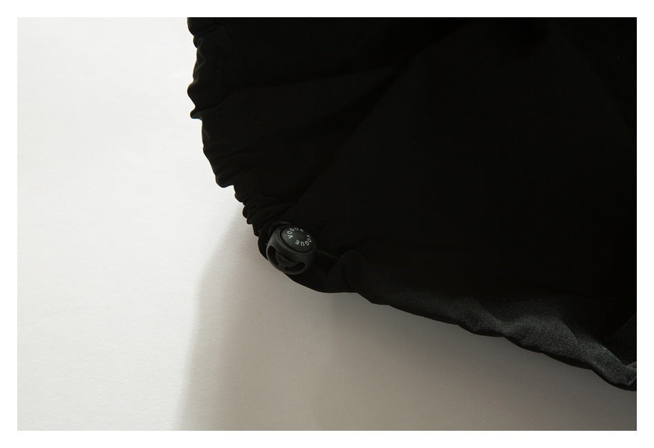 Close-up of black garment fabric with a gathered edge and round drawcord toggle.