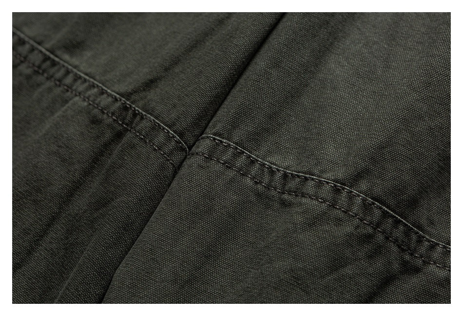 Close-up of olive trousers showing a diagonal stitched seam and textured fabric.