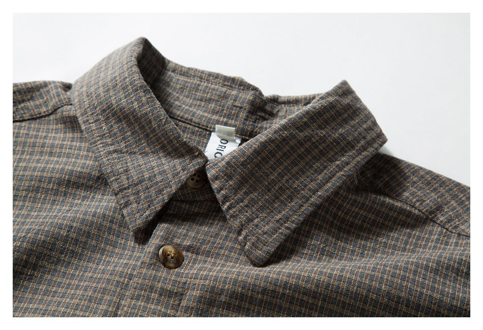 Close-up of the pointed collar and buttons on a brown and blue small-check shirt.