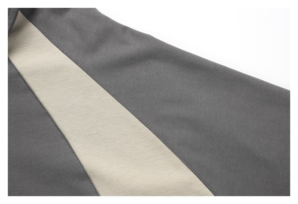 Close-up of a charcoal gray garment with a light beige curved colorblock panel.