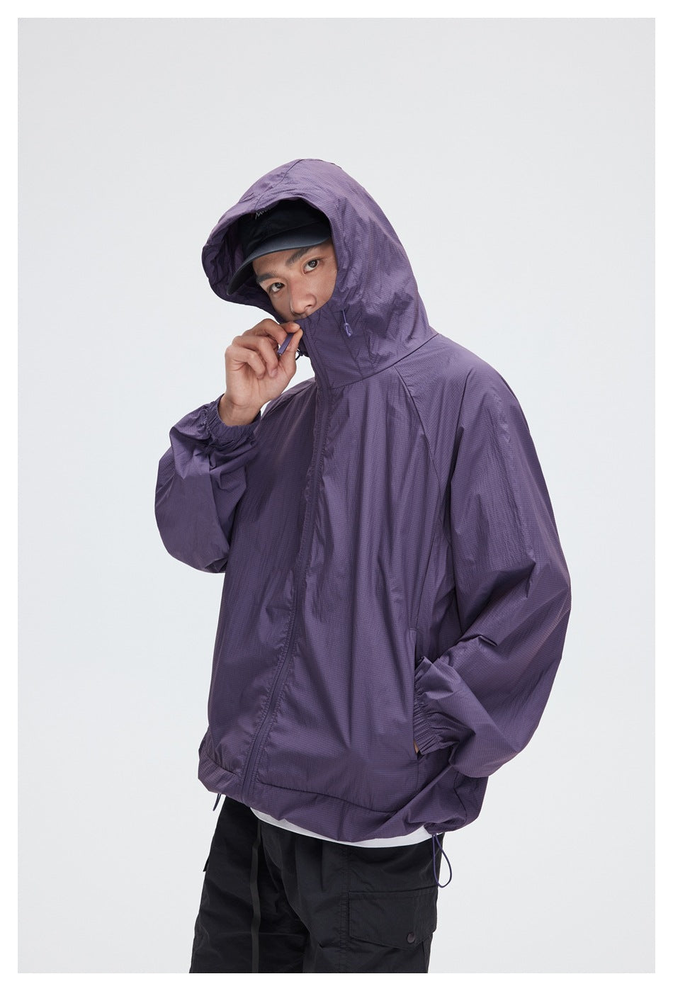Person wearing a purple hooded zip jacket with the hood raised and black shorts.