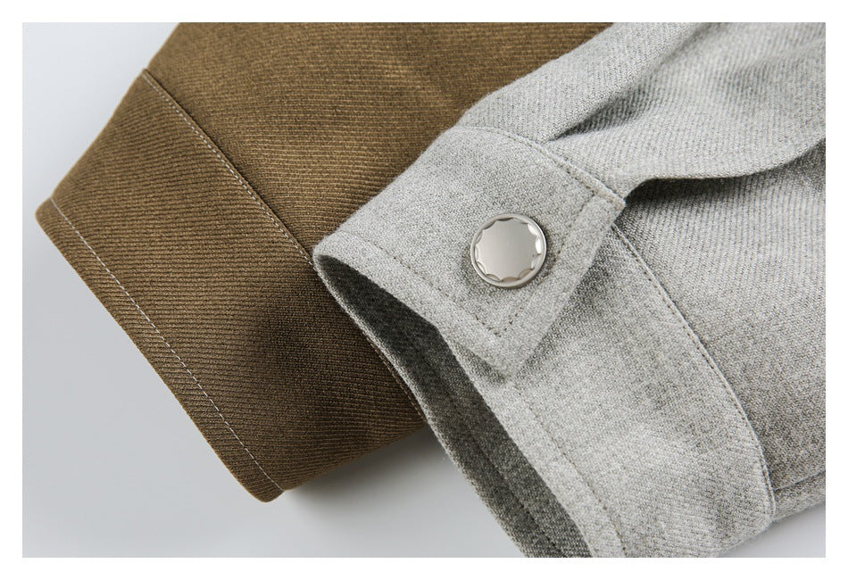 Close-up of a light gray garment panel with a silver button overlapping a brown ribbed cuff.