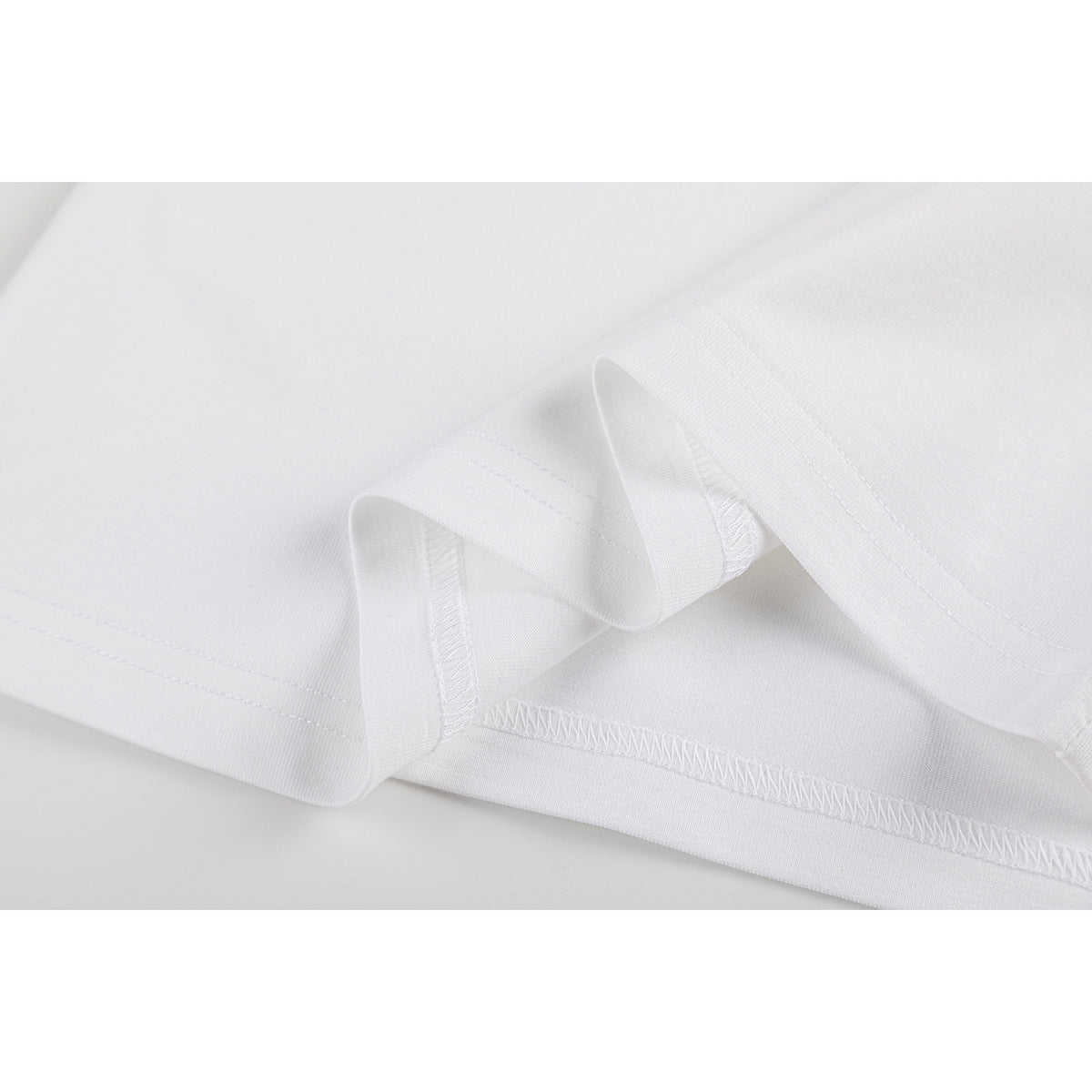 Close-up of the white T-shirt's folded hem and overlocked stitching.