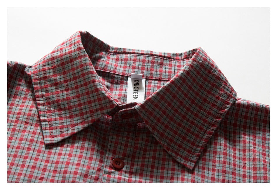 Close-up of the collar and top button of a red, gray, and blue plaid shirt.