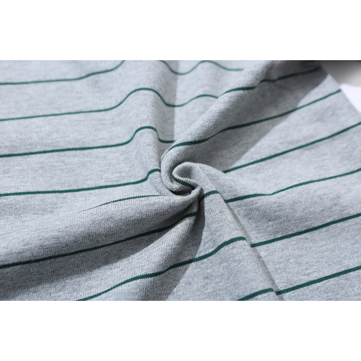 Close-up of gray knit fabric with thin dark green horizontal stripes, gathered into a fold.