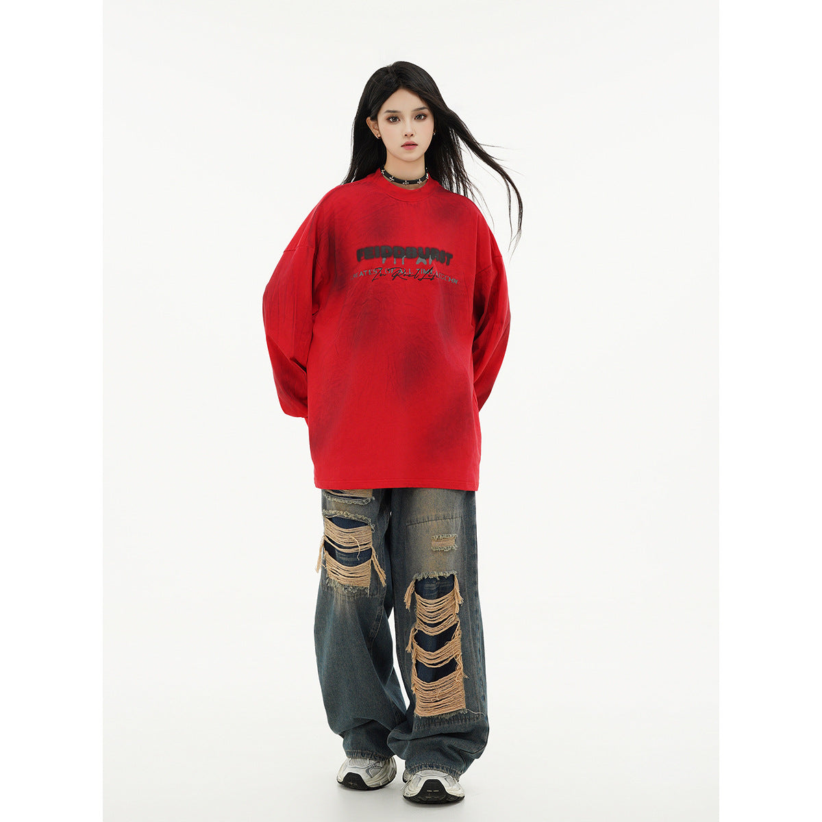 Full-length model wearing an oversized red graphic long-sleeve shirt and distressed wide-leg jeans.