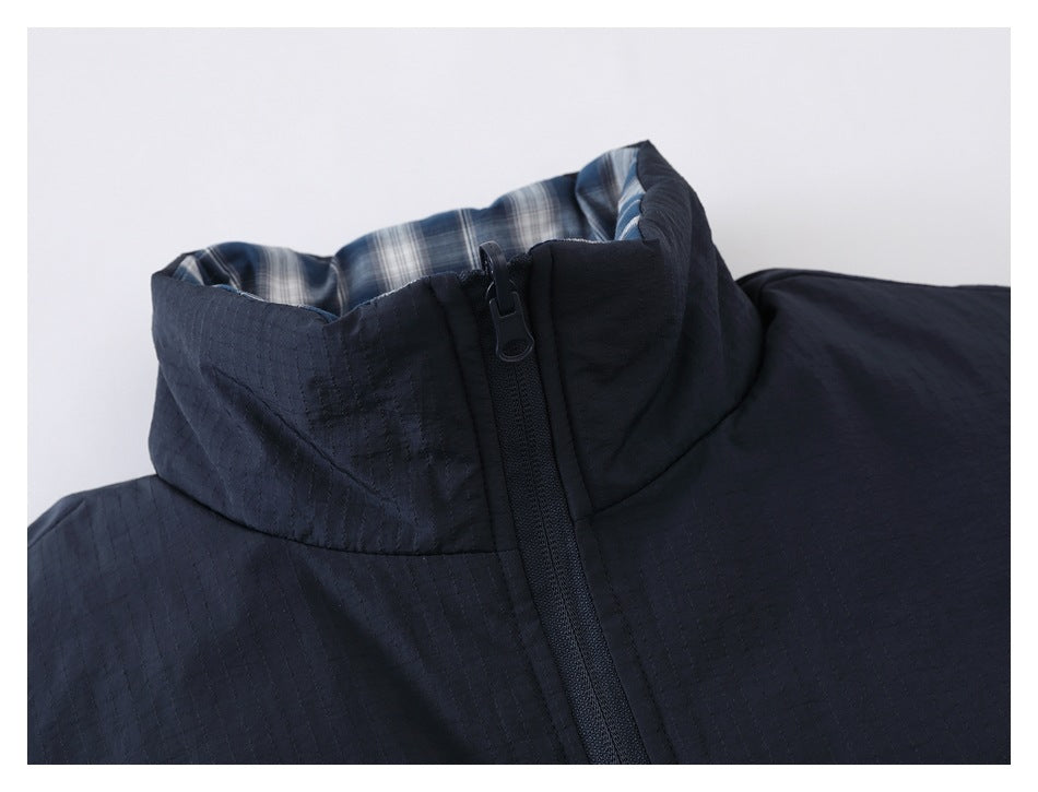 Close-up of a navy jacket's high collar, front zipper, and blue-and-white plaid lining.