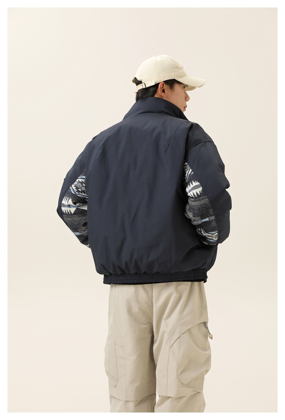 Back view of a model wearing a navy jacket with patterned fabric panels along the sleeves.