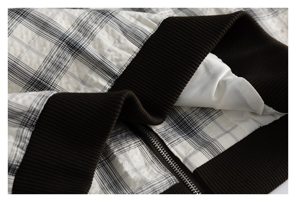 Close-up of plaid garment fabric with black ribbed trim and a silver zipper.
