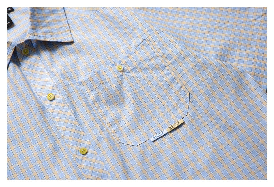 Flat-laid light blue and beige plaid shirt showing its chest pocket and yellow-button placket.