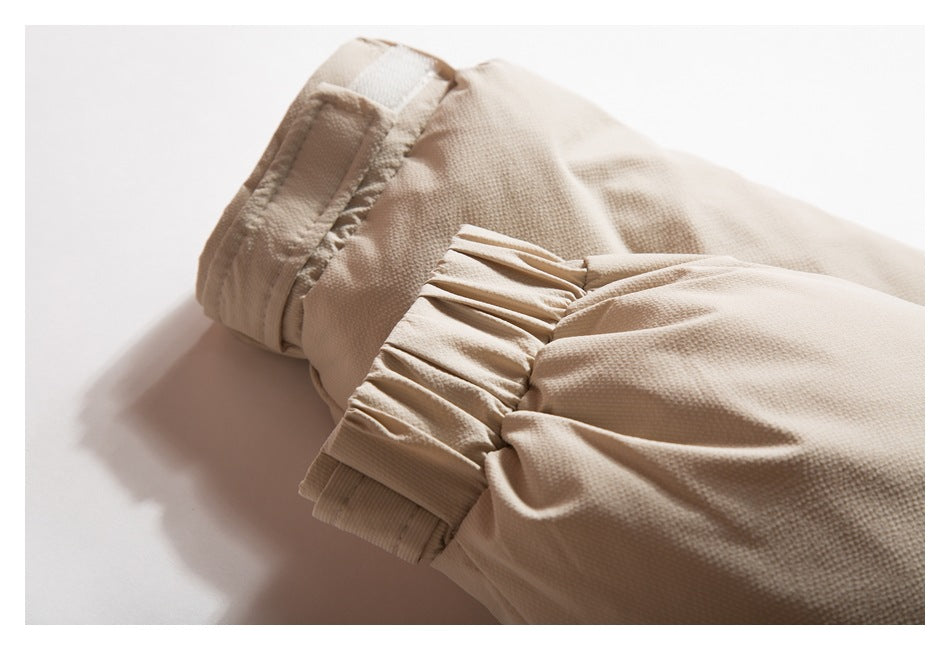 Close-up of a beige garment cuff with gathered pleats and stitched bands.