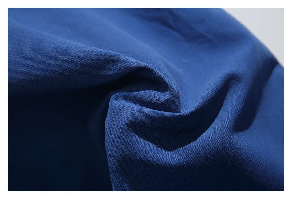 Macro view of royal-blue trouser fabric draped into soft folds, showing its textured surface.
