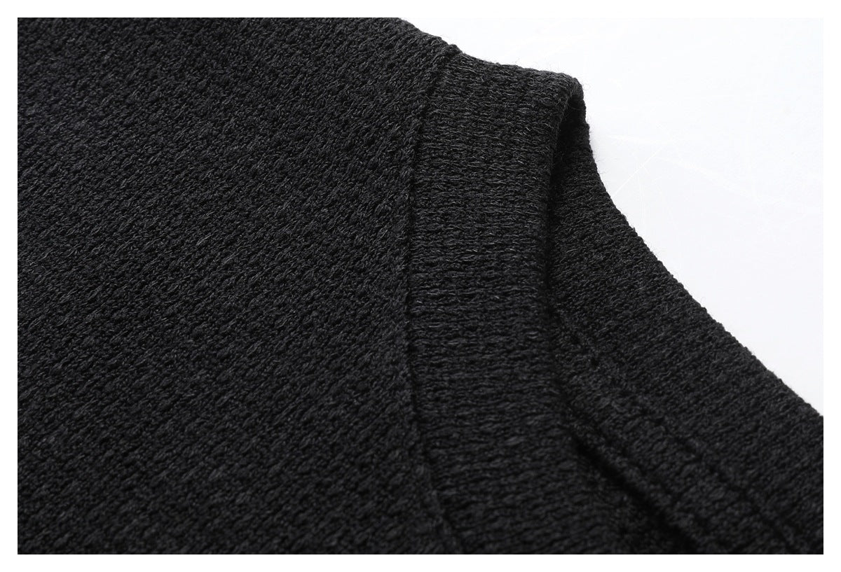 Close-up of black textured fabric and a ribbed neckline seam on the shirt.