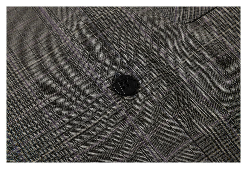 Close-up of the gray plaid fabric and a black four-hole shirt button.