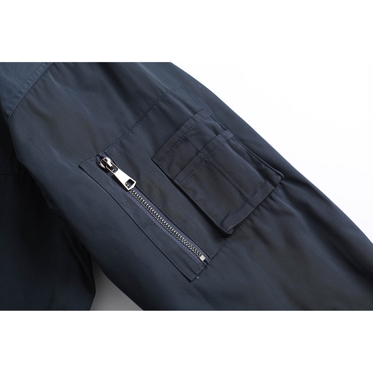 Close-up of a dark navy jacket sleeve with a zip pocket and a flap pocket.