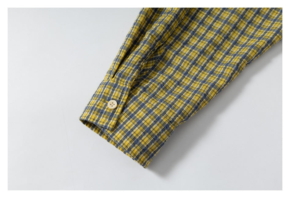 Close-up of a buttoned cuff on a yellow and navy plaid sleeve.