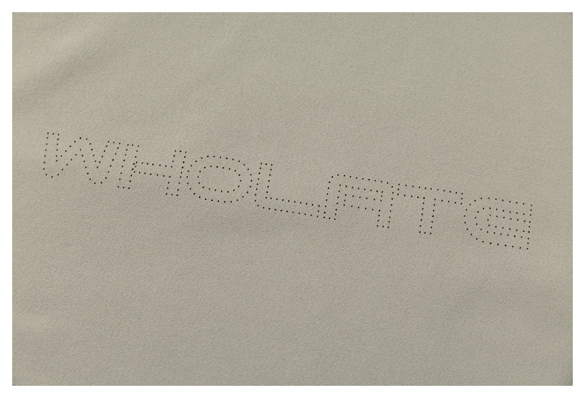Close-up of dotted lettering printed across the light taupe T-shirt.