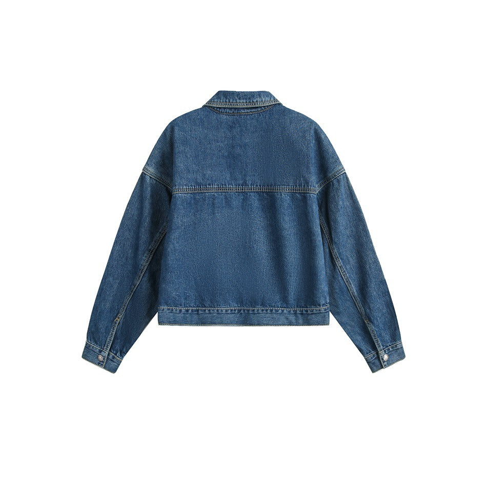 Back view of a blue denim jacket laid flat, showing its collar, yoke seam, long sleeves, and button cuffs.