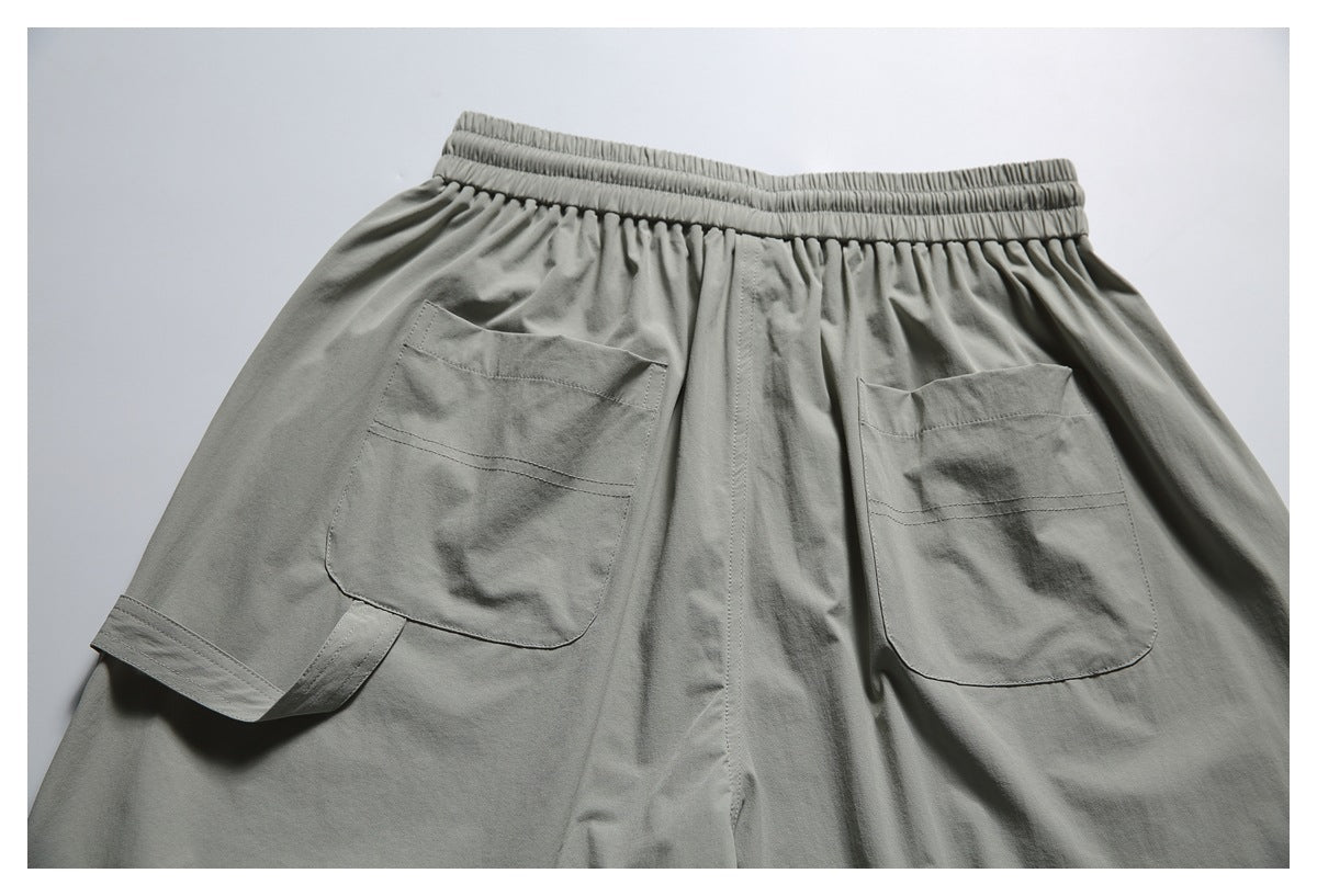Back view of gray-green shorts laid flat, showing an elastic waistband and two patch pockets.