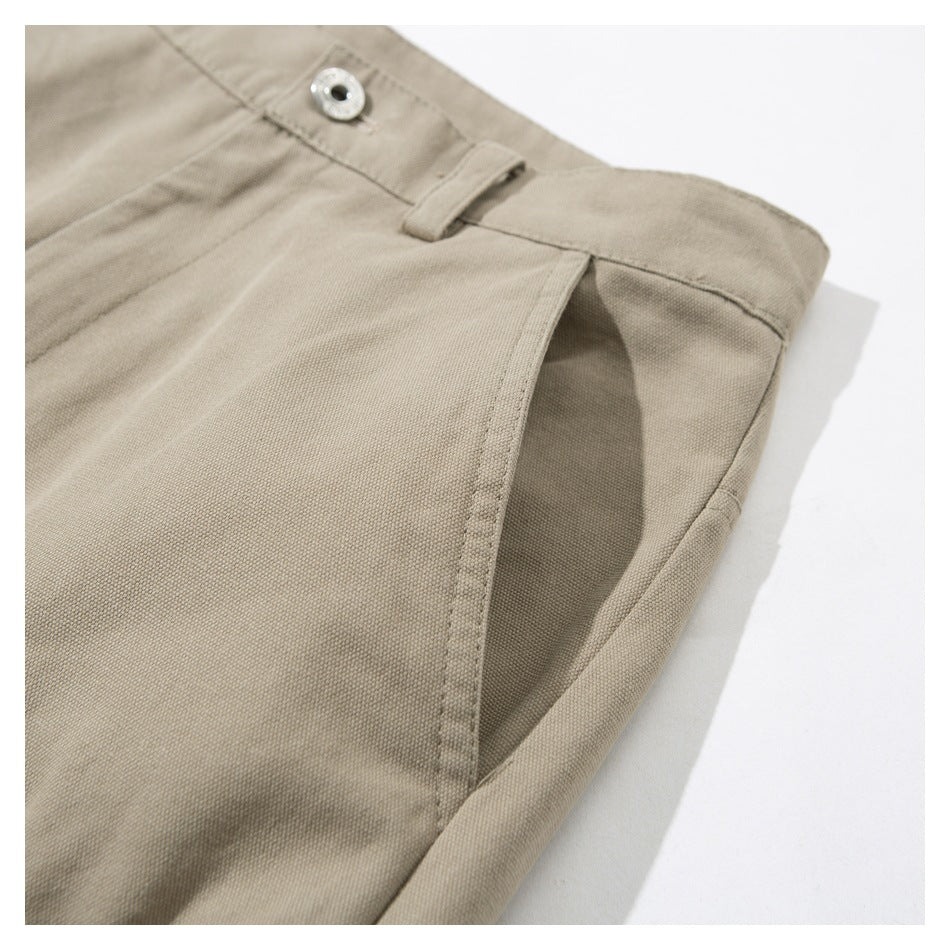 Close-up of beige trousers showing a buttoned waistband, belt loop, and slanted front pocket opening.