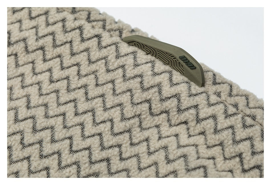 Close-up of beige zigzag-patterned fabric beside a small olive-colored plastic fastener.
