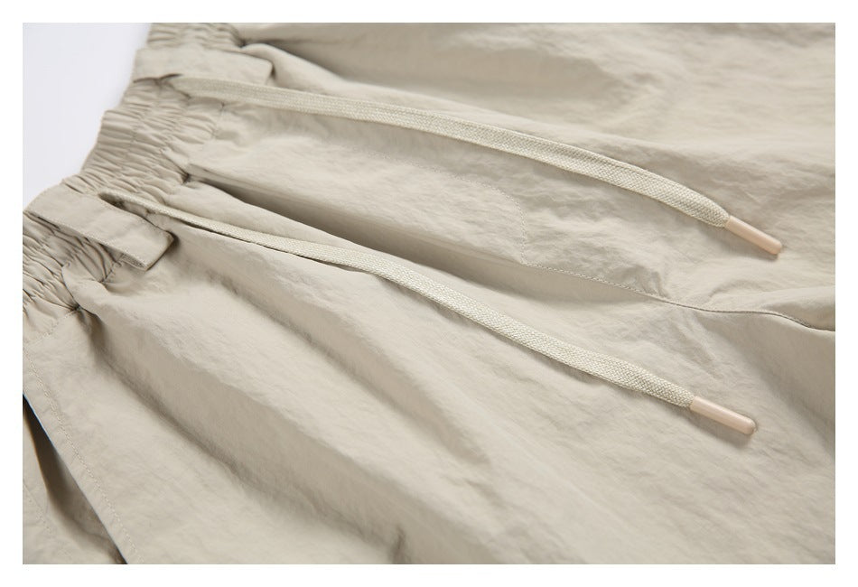 Light beige pants waistband with two drawstrings and the top of a front pocket.