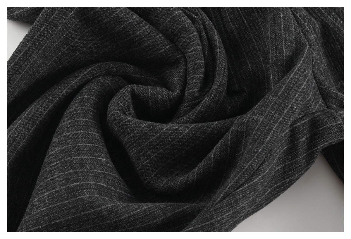 Close-up of charcoal pinstripe trouser fabric draped into folds.