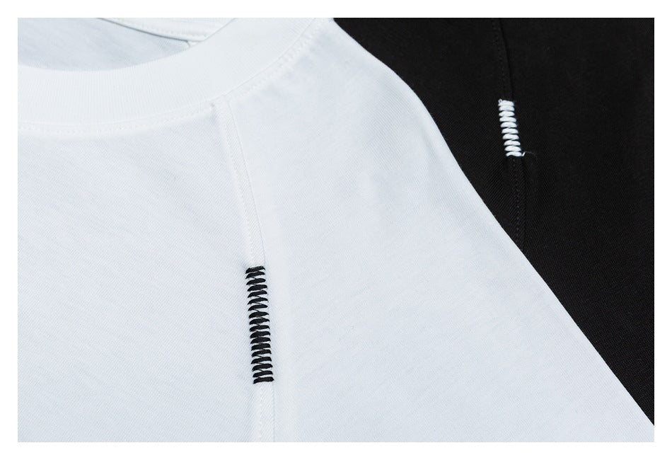 Close-up of white and black garments with contrasting decorative stitches at the seams.